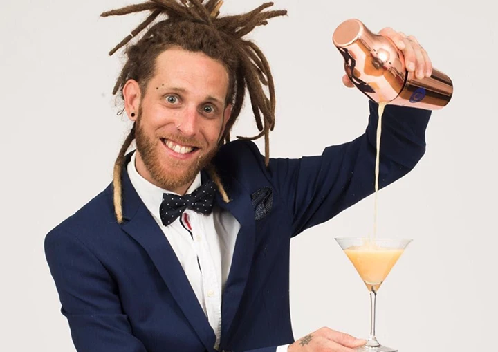 Imagen de un barman sonriente mientras prepara un cóctel 